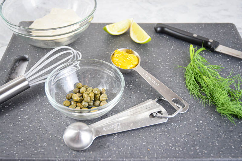 Dill sauce ingredients prepped on a grey cutting board.