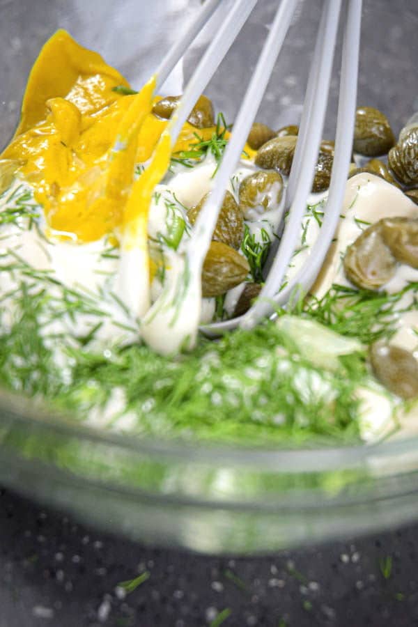 A whisk mixing up dill dip ingredients.