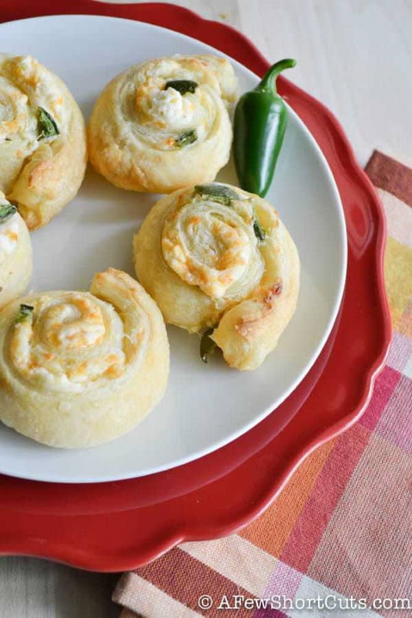 Jalapeno pinwheels appetizer on a white plate with a red plate underneath.