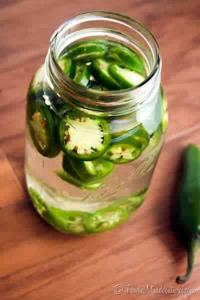 Jalapeno infused tequila in a jar, wooden background.
