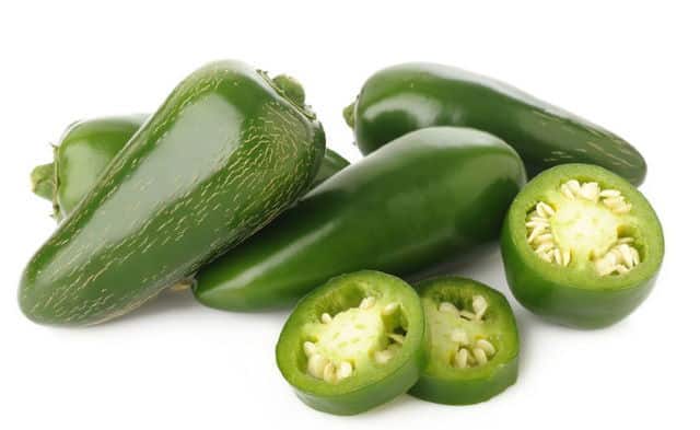 Green jalapeno chili peppers, sliced and whole. White background.