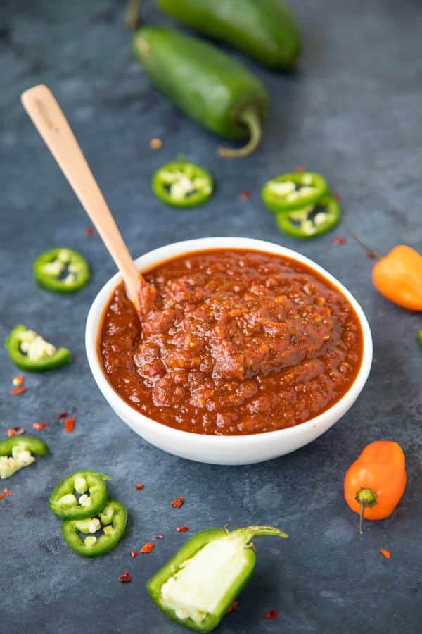 Honey BBQ sauce in a small white dish, chili peppers on the side.