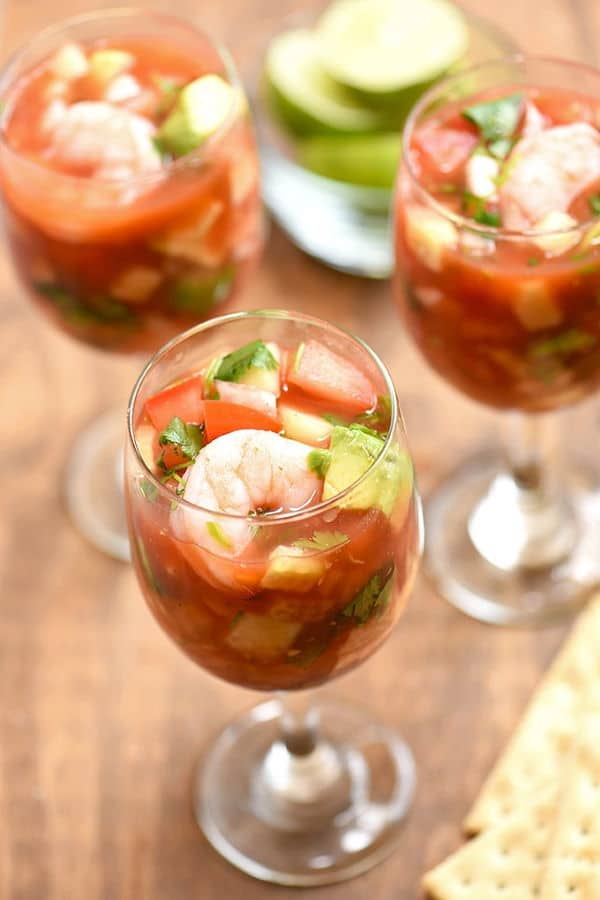 Shrimp cocktail in 3 wine glasses, wooden background.