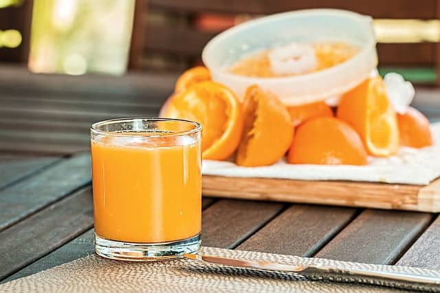 Fresh orange juice in a glass, wooden background.