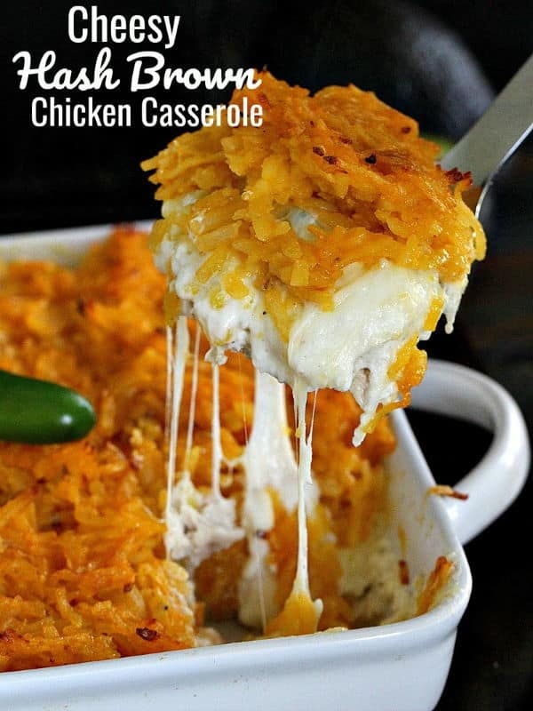Hash brown casserole, a piece being scooped with melted cheese pulling apart.