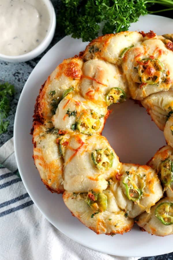 jalapeno popper monkey bread on a white plate, dish towel underneath.