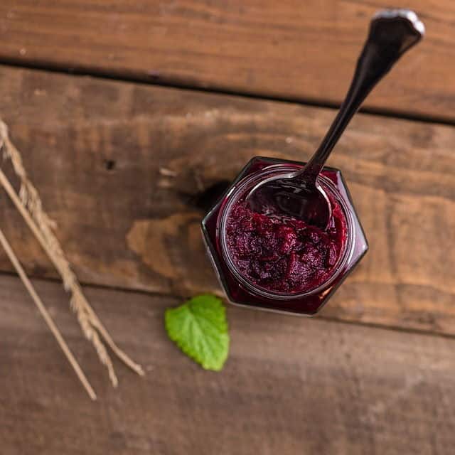 Red jam in a jar, wooden background.