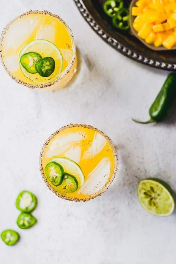 2 glasses of spicy mango margarita on marble countertop.