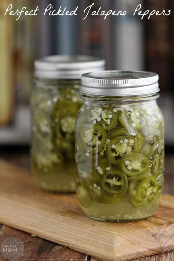 Pickled jalapeno slices in 2 canning jars, wooden background.