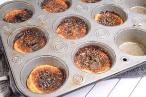 Baked butter tarts in a muffin tin.