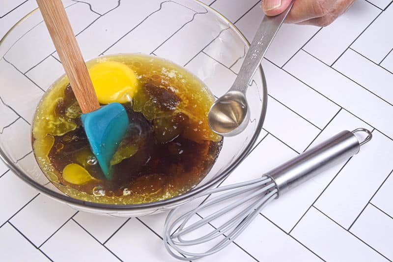 How to Make Butter Tarts_5 Butter, vinegar, maple syrup, eggs and brown sugar in a bowl, whisk on the side, white background.