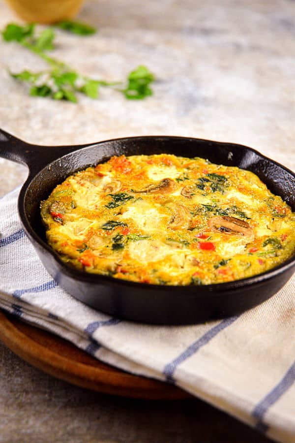 Electric Skillet Vegetable and Goat Cheese Frittata on a pie server and in a cast iron pan.