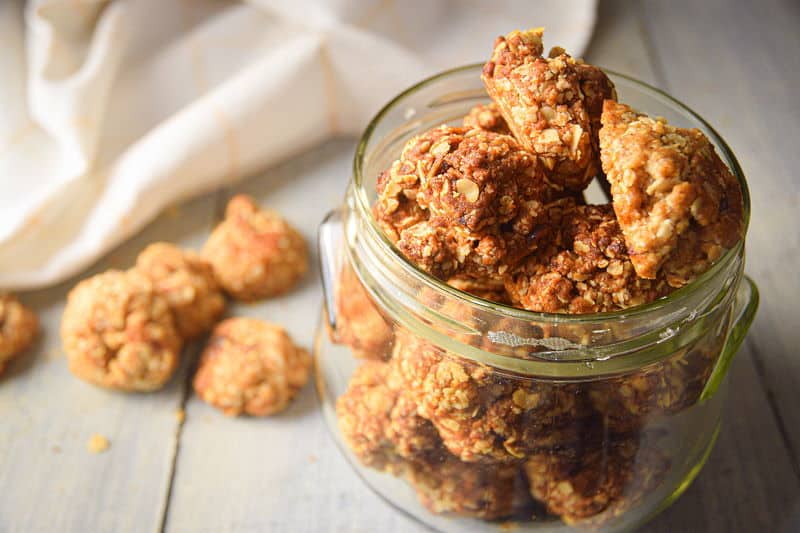 Electric Skillet Oatmeal Cookies in a clear jar, on white wooden background.