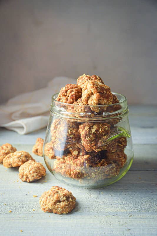 Electric Skillet Oatmeal Cookies in a clear jar, on white wooden background.