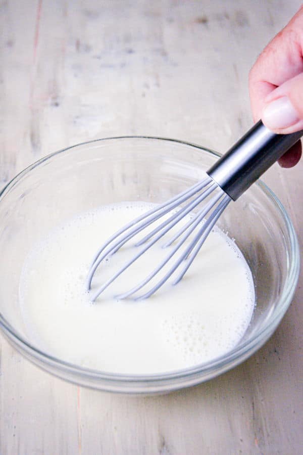 Hot milk in a bowl with a whisk.