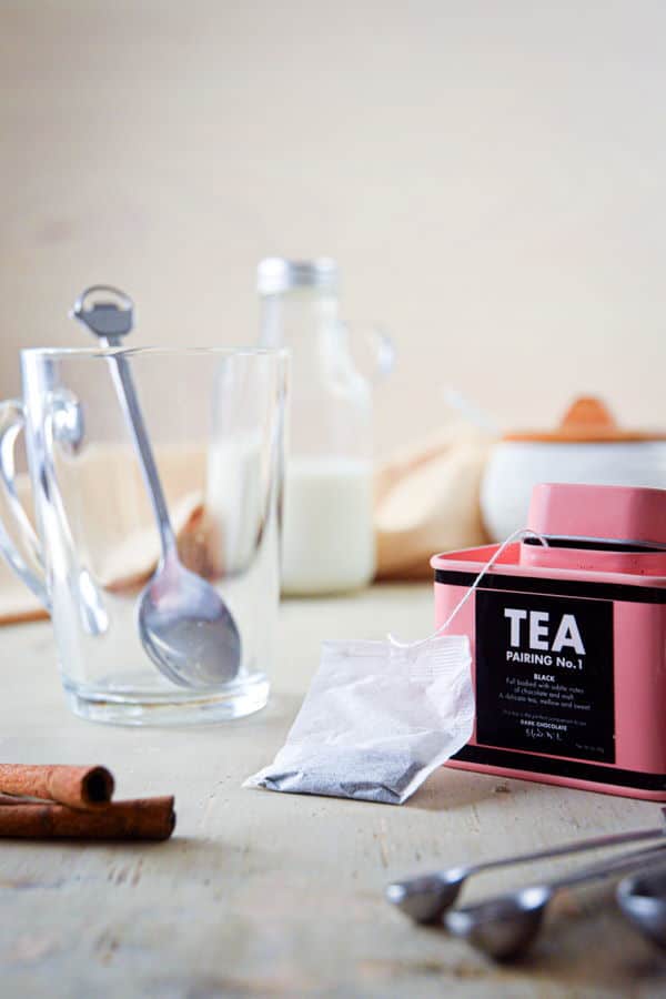 Earl grey tea, clear glass mug, mixing spoon, cinnamon on wooden background.