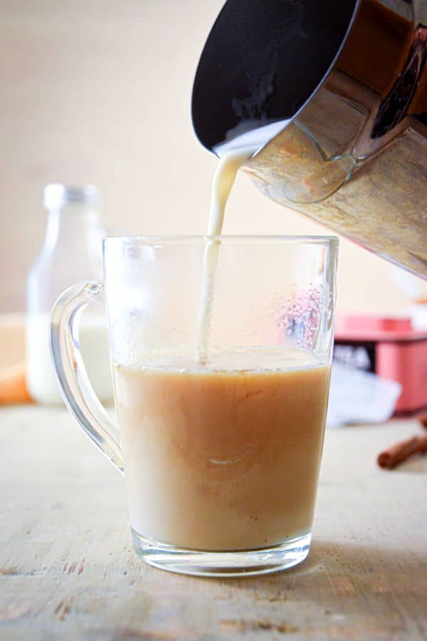 Hot milk and a london fog in a clear glass mug.