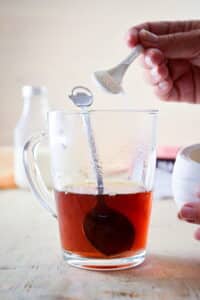 Earl grey tea, steeped in a clear glass mug with sugar.
