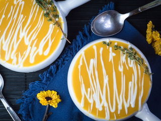Pumpkin Cream Soup with Orange & Drizzled Yogurt Dressing, on blue cloth.