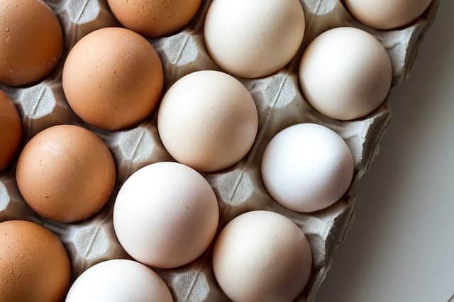 White and brown eggs in a carton.