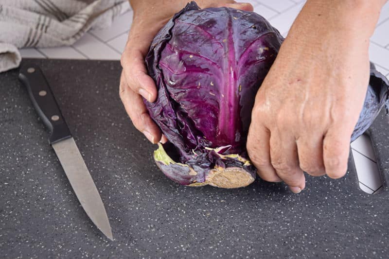 Red cabbage and knife on cutting board.