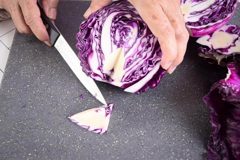 Red cabbage and knife on cutting board.