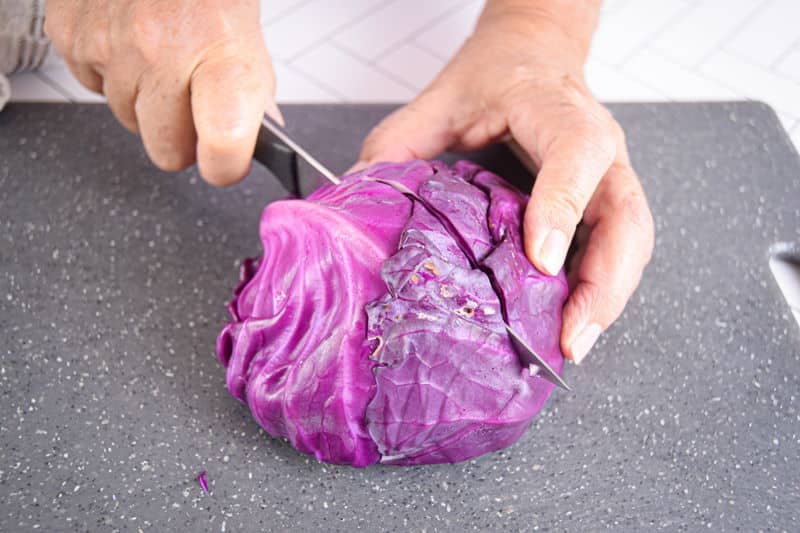 Red cabbage and knife on cutting board.