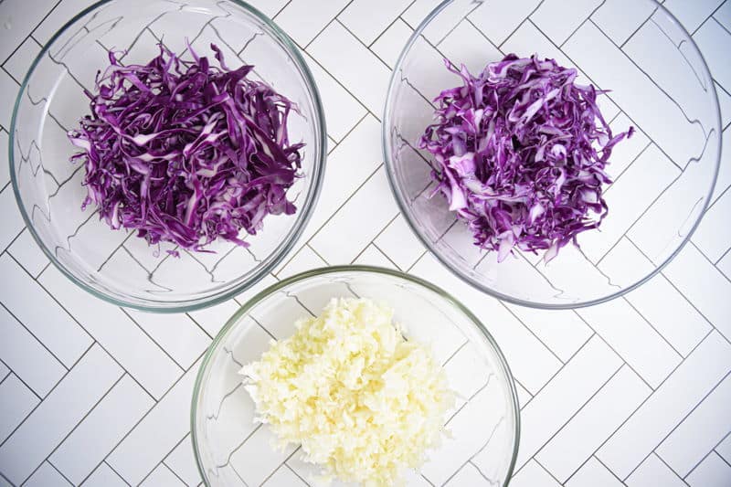 Three bowls each with shredded cabbage on white background.
