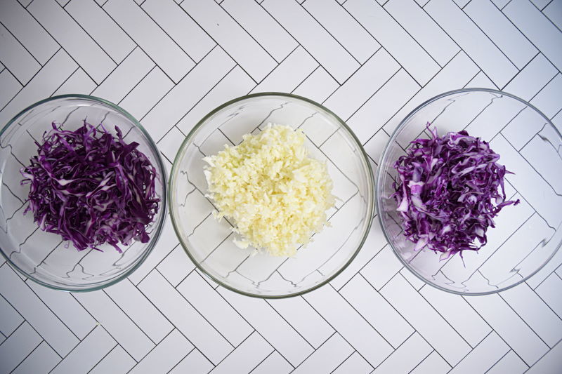 Three bowls each with shredded cabbage on white background.
