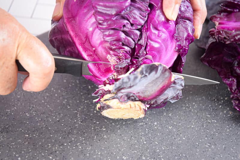 Red cabbage and knife on cutting board.