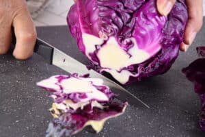 Red cabbage and knife on cutting board.