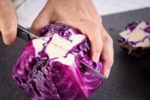 Red cabbage and knife on cutting board.