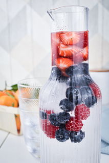 A glass pitcher filled with ice and berries.