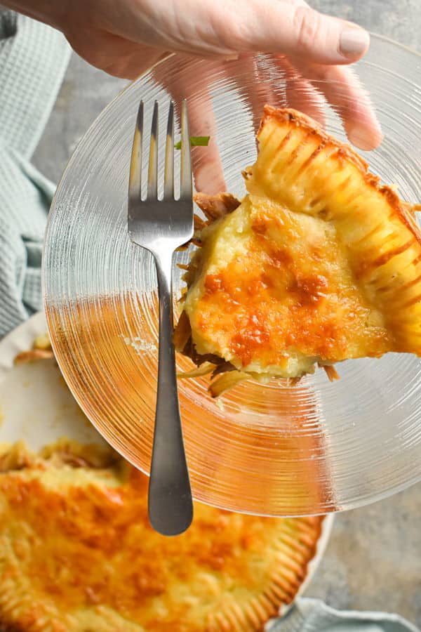 Shepherd's pie on a light towel, and one slice on a clear glass plate with a fork.