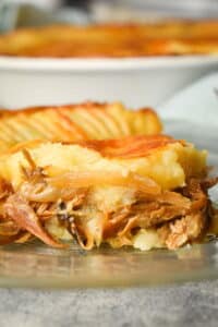 One slice of Shepherd's pie on a clear glass plate.