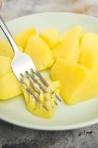 Boiled potatoes on a plate, with a fork.