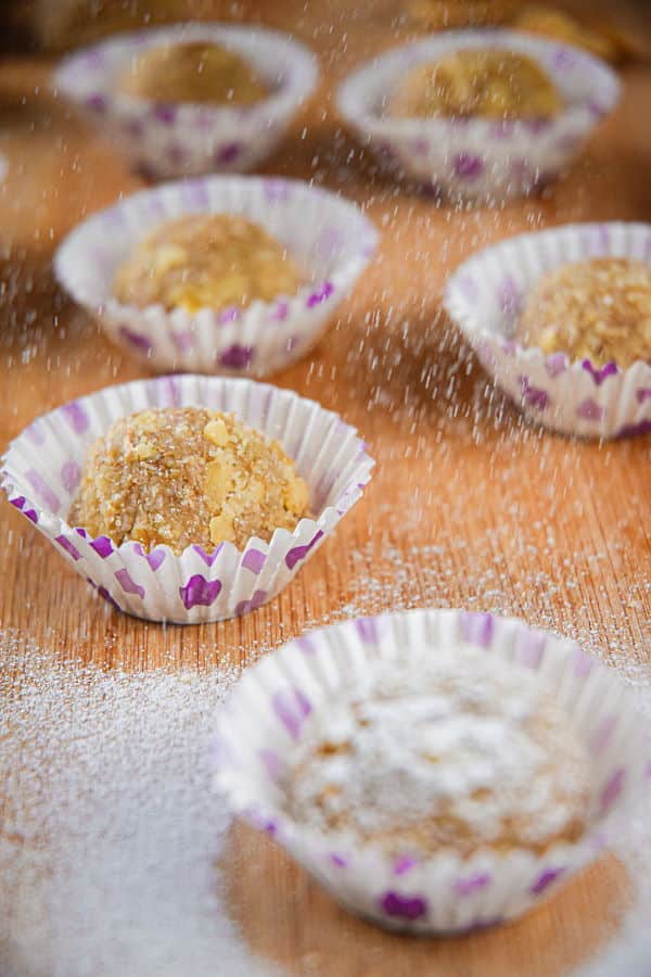 Marzipan Nut Balls in purple and white baking cups, on wooden background.