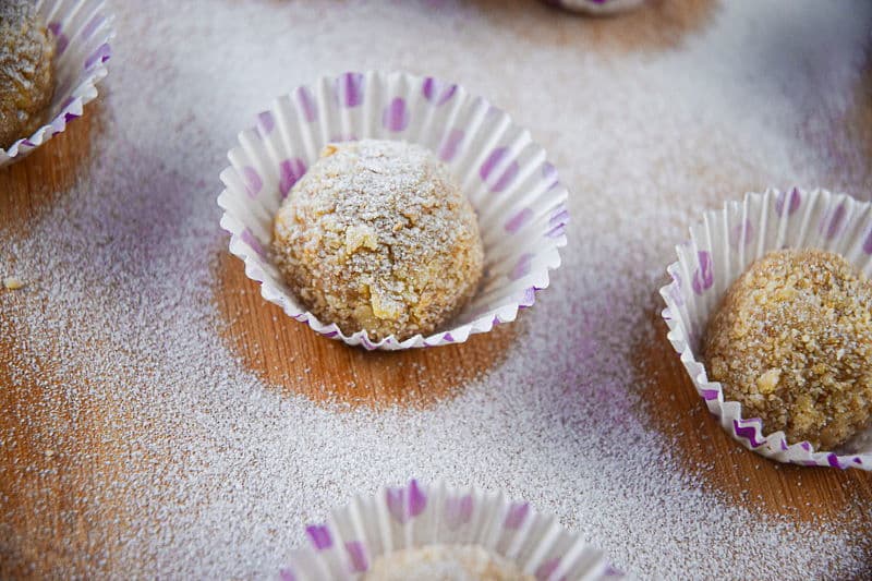 Marzipan Nut Balls in purple and white baking cups, on wooden background.