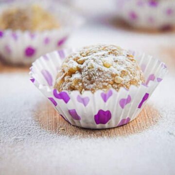 Marzipan Nut Balls in purple and white baking cups, on wooden background.