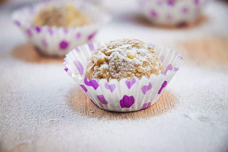 Marzipan Nut Balls in purple and white baking cups, on wooden background.