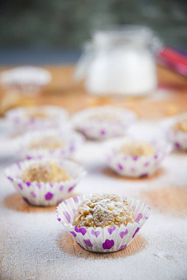 Marzipan Nut Balls in purple and white baking cups, on wooden background.