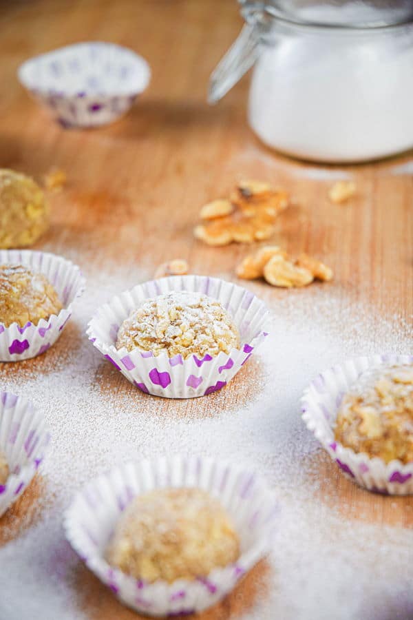 Marzipan Nut Balls in purple and white baking cups, on wooden background.