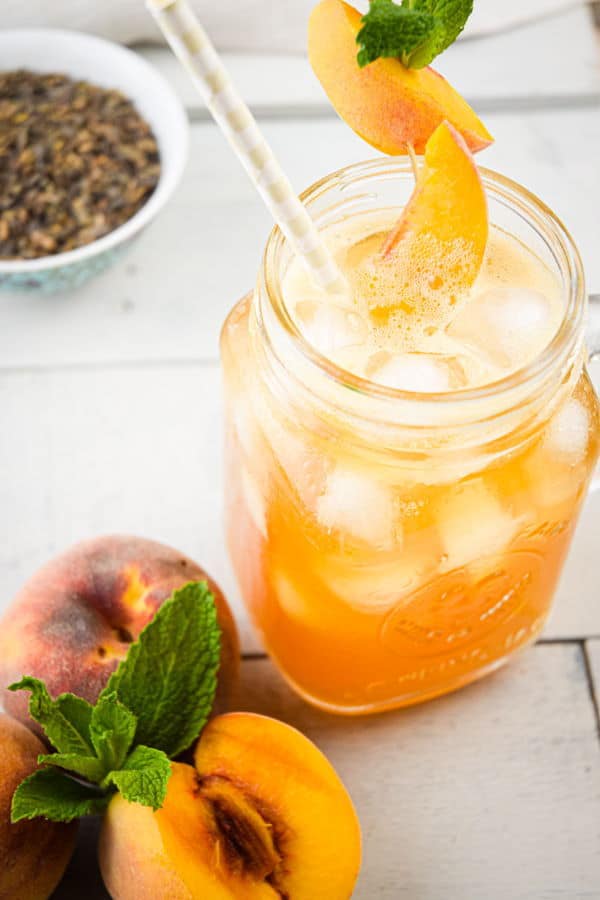 Peachy Iced Green Tea-8 Peachy Iced Green Tea in a mason jar glass, a small bowl of tea leaves and peaches on the side.