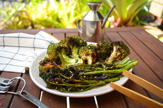 Grilled broccoli on dish and wooden table.