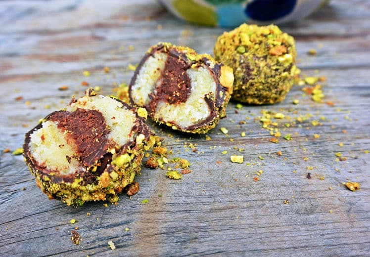 Marzipan truffles with pistachios on wooden background.