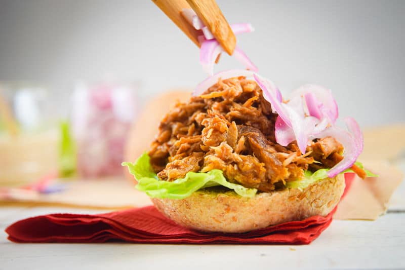 Pulled pork sliders with red white and blue flag toothpicks on white wooden background.