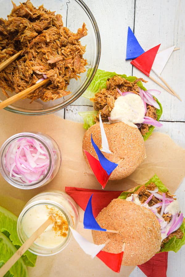 Pulled pork sliders with red white and blue flag toothpicks on white wooden background.