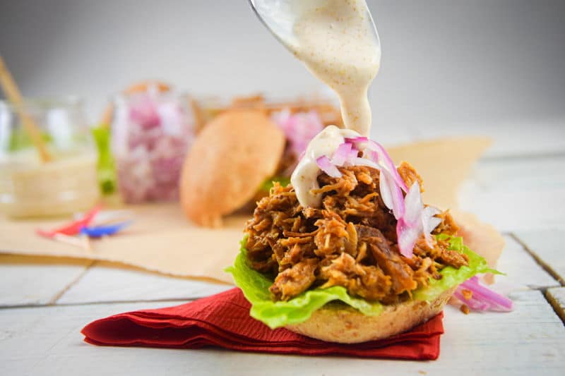 Pulled pork sliders with red white and blue flag toothpicks on white wooden background.