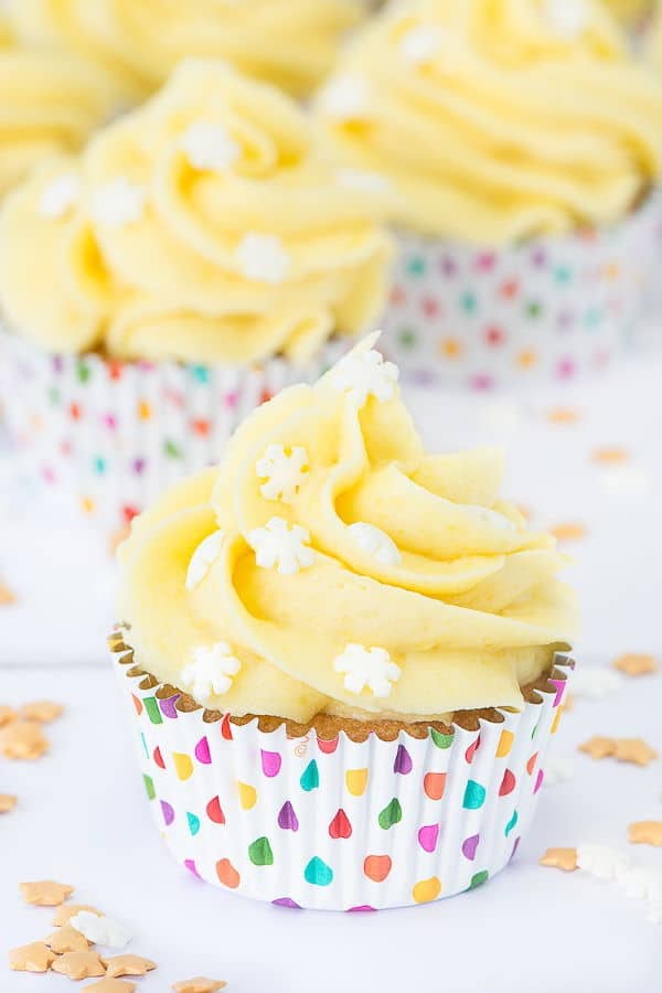 Marzipan buttercream cupcakes on white background with sprinkles.