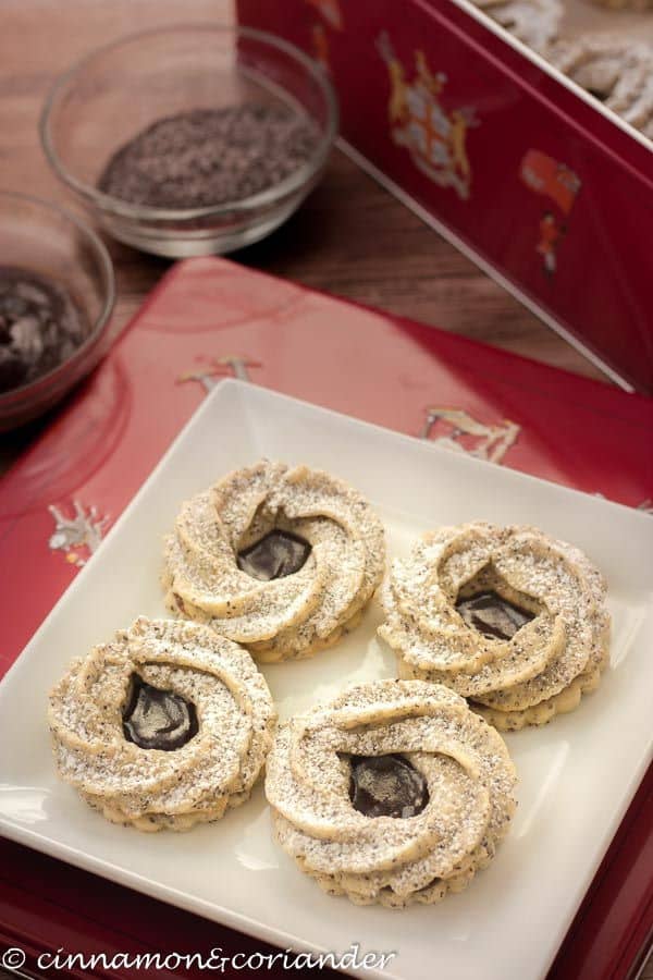 Marzipan cookies on a white plate, a red decorative box in the background.